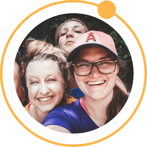 A circular image of 3 women smiling with an orange circle outline with a smaller circle overlapping it